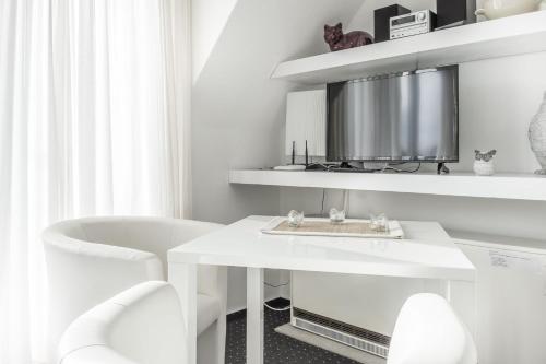 a white bathroom with a white table and chairs at Sandkorn-Büsum in Büsum