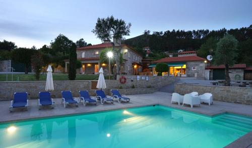 a swimming pool with chairs and umbrellas next to a building at Casa da Torre in Pico