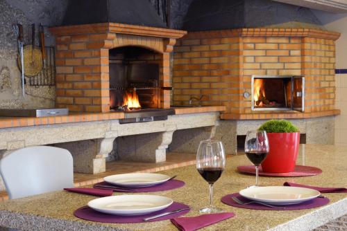 a table with two glasses of wine and a brick oven at Casa da Torre in Pico