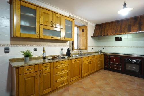 a kitchen with wooden cabinets and a sink and a stove at Casa da Torre in Pico