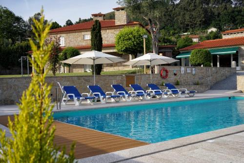 a group of chairs and umbrellas next to a swimming pool at Casa da Torre in Pico