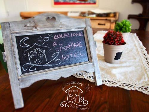 a chalkboard sign on a table with a potted plant at Casamare Hotel in San Vincenzo