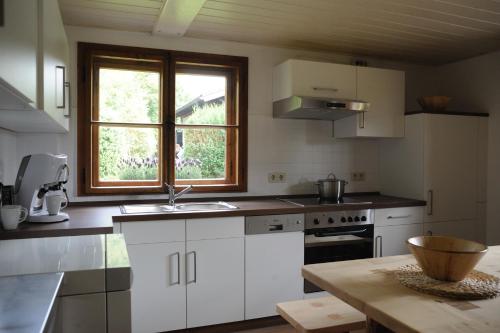 una cocina con armarios blancos y una ventana en Ferienhaus BERGEBLICK 5S, en Bad Tölz