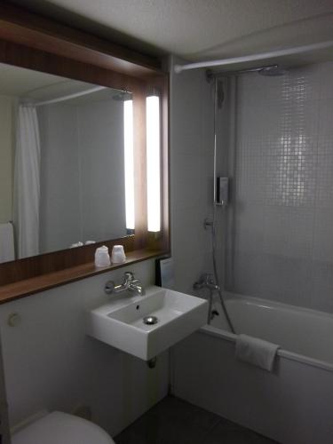 a bathroom with a sink and a toilet and a mirror at Campanile Villennes-Sur-Seine - Poissy - Hôtel rénové en 2024 in Villennes-sur-Seine