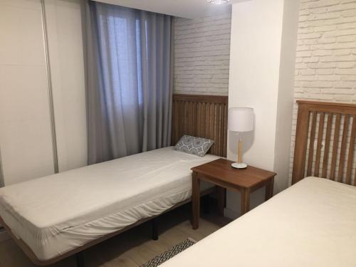 ein Schlafzimmer mit 2 Betten und einem Tisch mit einer Lampe in der Unterkunft ConMdeMálaga San Millán Centro in Málaga