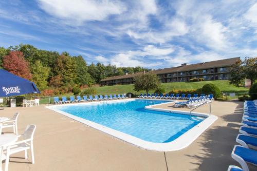 a large swimming pool with blue chairs and a building at Fox Ridge Resort in North Conway