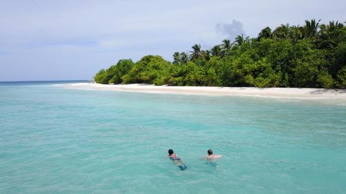 two people swimming in the ocean near a beach at Holiday Haven Ukulhas in Ukulhas