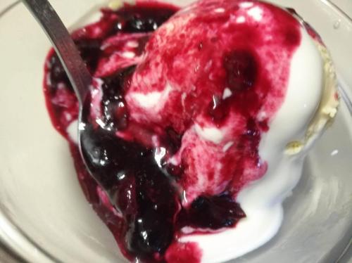 a spoon in a bowl of blueberry sauce and whipped cream at Schwaighof in Oberau