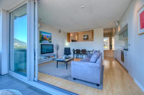 a living room with a couch and a tv at Swiss-Belsuites Pounamu Queenstown in Queenstown