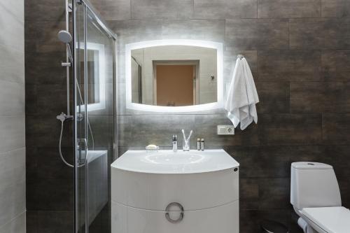 ein Badezimmer mit Waschbecken und Dusche mit Spiegel in der Unterkunft Arcadia Villa Apartments in Odessa