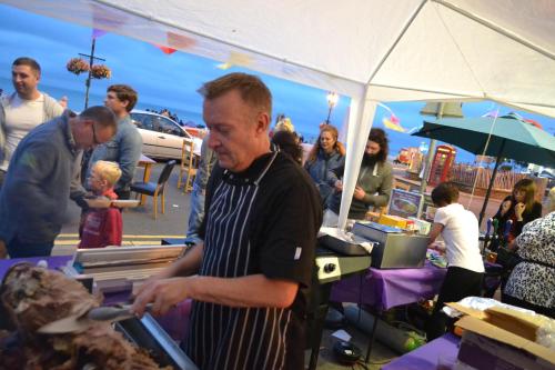 a man in an apron standing in a market at Waterfront Hotel in Deal