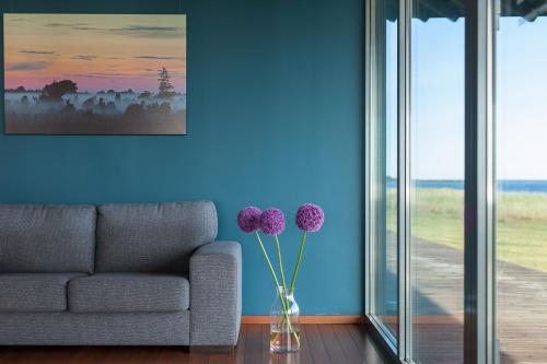a living room with a couch and a vase with purple flowers at Harbor House Lõmala in Lõmala