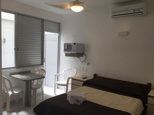 a bedroom with a bed and a table and chairs at Pousada e Camping Lagoa da Conceição in Florianópolis