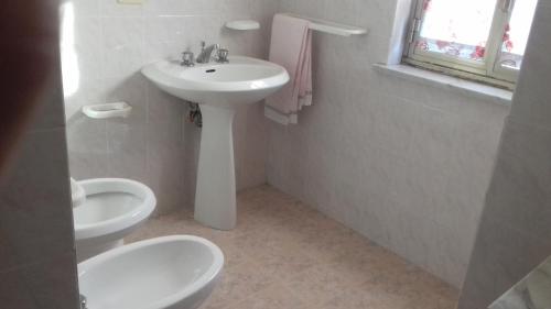 a white bathroom with a sink and a toilet at Appartamento mare blu Pachino in Pachino