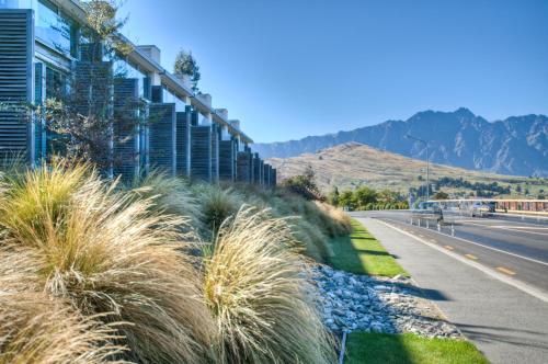 a road with tall grass next to a building at Swiss-Belsuites Pounamu Queenstown in Queenstown