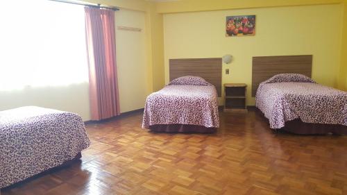 a room with two beds and a wooden floor at Hotel Nuevo Sol in La Paz