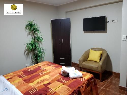 a bedroom with a bed and a chair and a television at Imperio Tanpu Q in Lima
