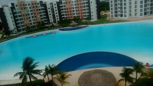 a large swimming pool with palm trees and buildings at Departamento en Dream Lagoons Cancun in Cancún