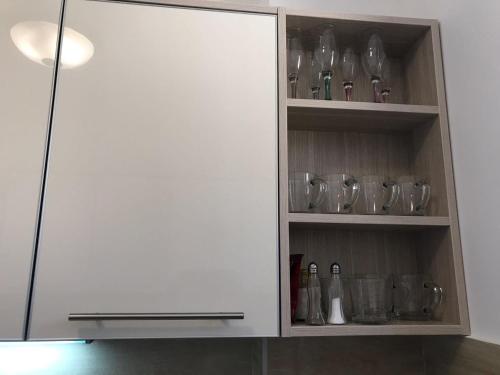 a white cabinet with glasses and bottles in it at ViLena Apartmani in Tivat
