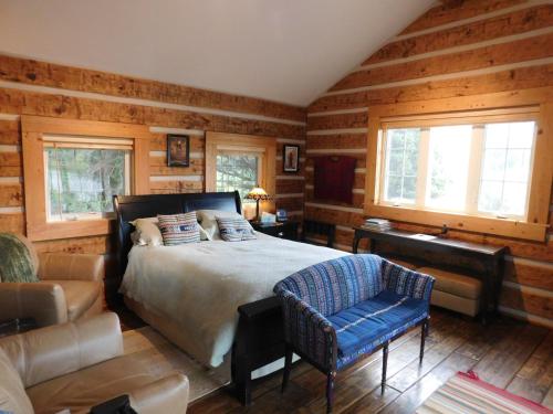 1 dormitorio con 1 cama, 1 silla y 1 sofá en Riverside Meadows Cabins en South Fork