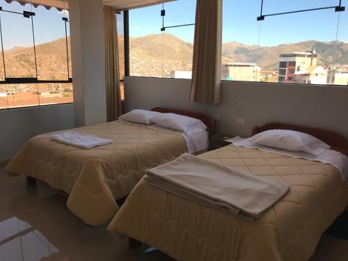 2 Betten in einem Zimmer mit 2 Fenstern in der Unterkunft Edmoli Casa Hospedaje in Cusco