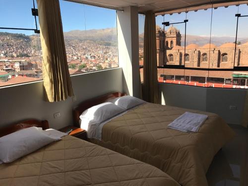 ein Hotelzimmer mit 2 Betten und einem großen Fenster in der Unterkunft Edmoli Casa Hospedaje in Cusco