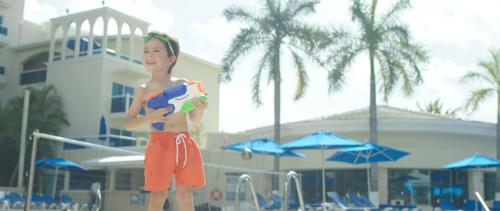 a young boy standing at the beach holding a toy at Occidental Costa Cancún - All Inclusive in Cancún