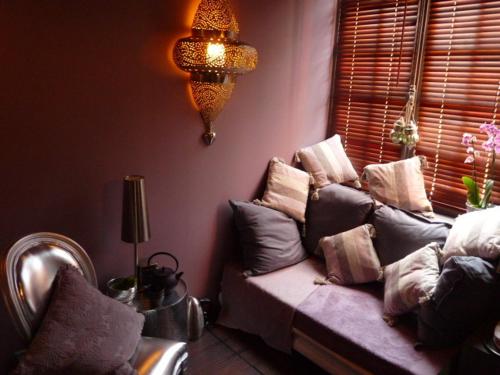 a living room with a couch with pillows on it at Chambres d'Hôtes & SPA Le Chat Chez Qui j'Habite in Saint-Aubin-sur-Mer