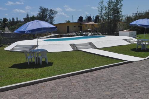 a swimming pool with two chairs and an umbrella at Hotel Azulejos in Chachalacas