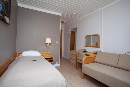 um quarto com uma cama, um sofá e um espelho em Stetind Hotel em Kjøpsvik