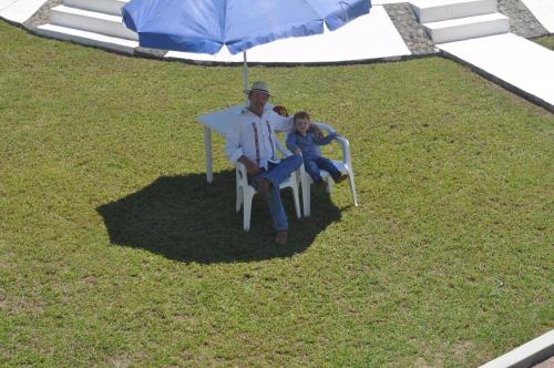 a man and a child sitting in a chair under an umbrella at Hotel Azulejos in Chachalacas