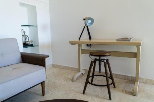 a desk and a stool next to a table and a chair at 3BR / 3BA Modern Paradise Loft Condo in Gated Community w/ Daily Housekeeping in Sosúa