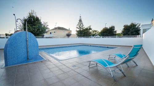 a swimming pool with a chair and a table and a chair at For Sea Apartment in Cabanas de Tavira