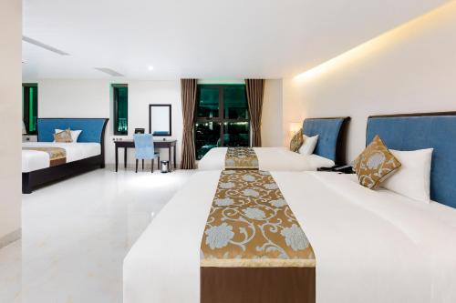 Habitación de hotel con 2 camas y escritorio en Royal Quang Binh Hotel, en Dong Hoi