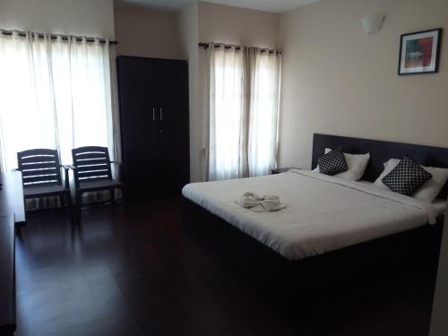 a bedroom with a large bed with white sheets and pillows at The Hill Side in Ooty