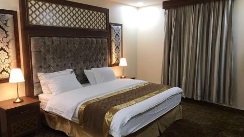 a bedroom with a large bed and two lamps at منازل الساهر للوحدات السكنية فرع 1 in Al Qunfudhah