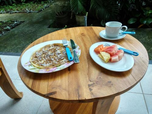 a table with two plates of pancakes and a cup of coffee at Batik Sekar Bali Guest House in Ubud