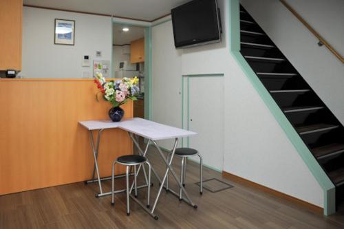una mesa y taburetes en una habitación con escalera en BJ Family House, en Kioto