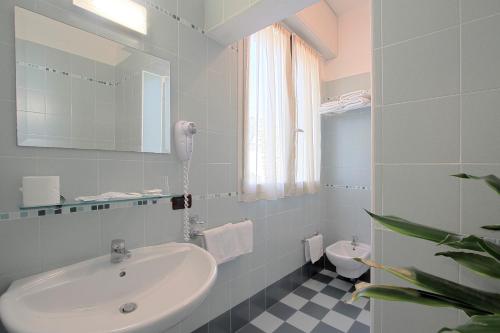 a white bathroom with a sink and a toilet at Hotel Corallo in Milano Marittima