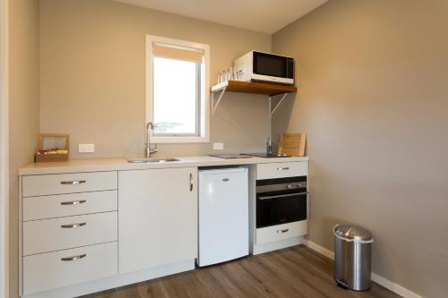 a kitchen with white cabinets and a sink and a window at Shotover Country Cottages in Queenstown
