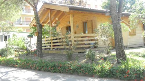 a wooden house with trees and flowers in front of it at Camping Daino in Pietramurata