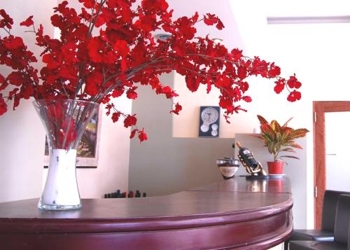 a vase filled with red flowers on a table at Hotel Gran Madryn in Puerto Madryn