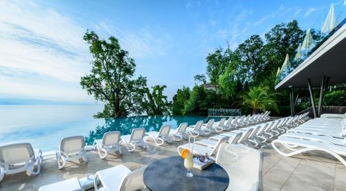a row of chairs and tables next to a swimming pool at Grand Hotel Adriatic II in Opatija