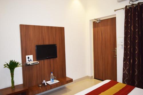 a bedroom with a television and a wooden door at Hotel Palace in Amritsar