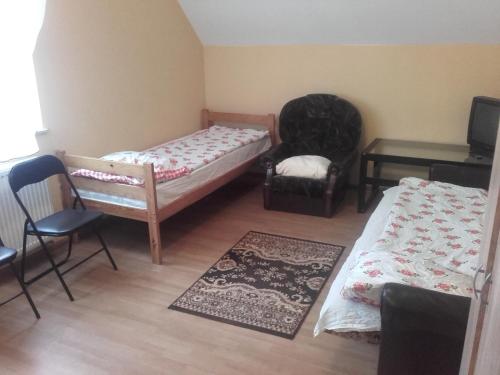 a small room with two beds and a chair at zajazd ''Marcówka" in Bakałarzewo