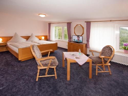 シュマレンベルクにあるPension Droste- Vogtのベッド、テーブル、椅子が備わるホテルルームです。