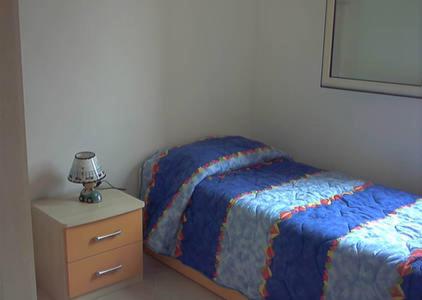 um quarto com uma cama e uma mesa de cabeceira com um candeeiro em Villetta Dolce em Campofelice di Roccella
