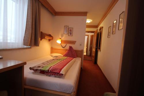 a small bedroom with a bed and a window at Hotel Garni Lärchenhof in Lech am Arlberg