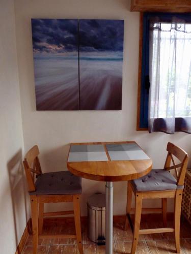 une table et deux chaises dans une pièce avec un tableau dans l'établissement Suite à 800m de la plage, à Saint-Lunaire