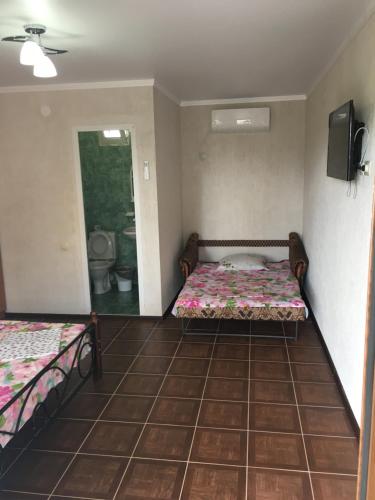 a bedroom with two beds and a tv in it at Guest house Kabardinskaya 121 in Gagra